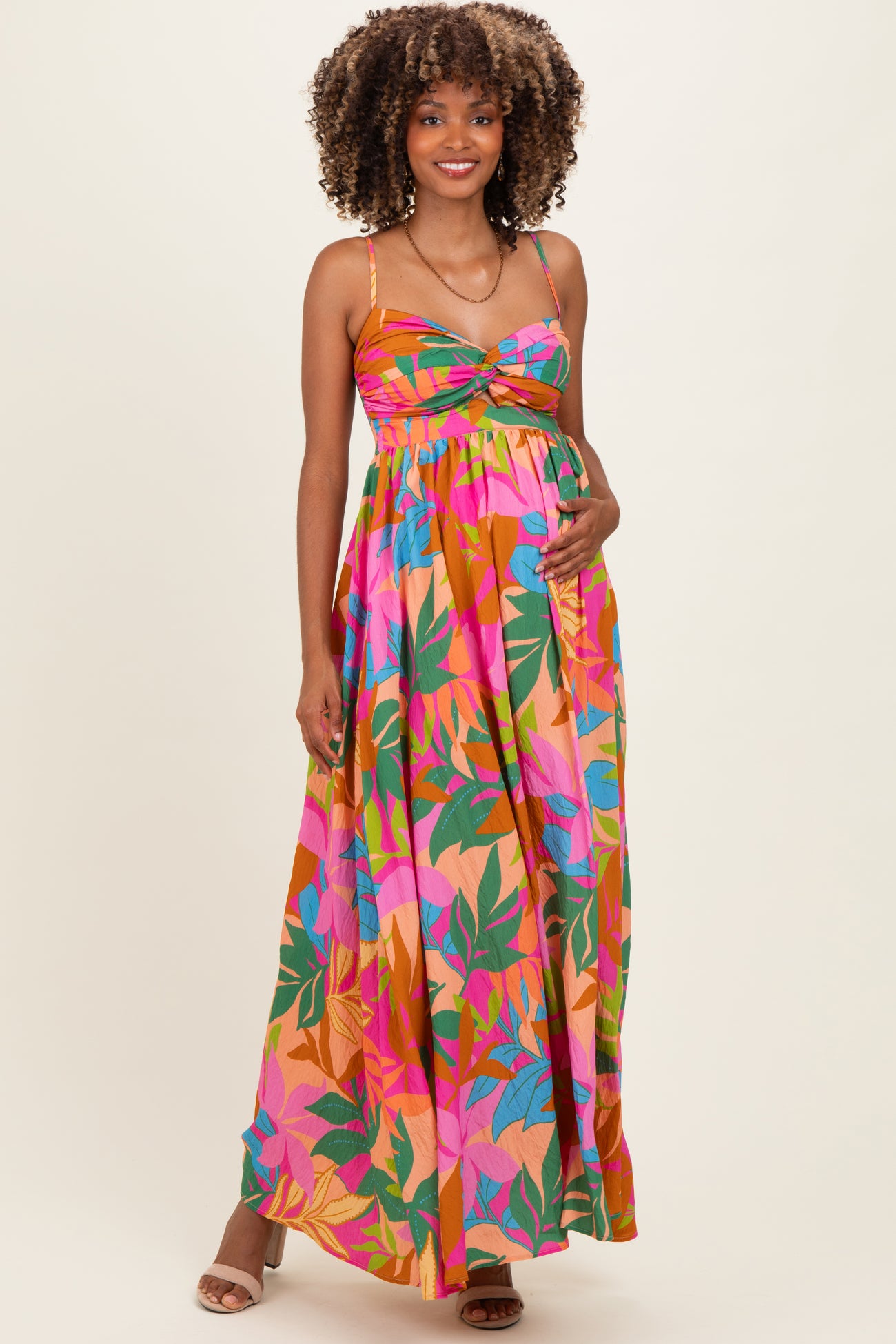 woman wearing a colorful floral maternity maxi dress with a twist front and adjustable straps, showcasing her baby bump