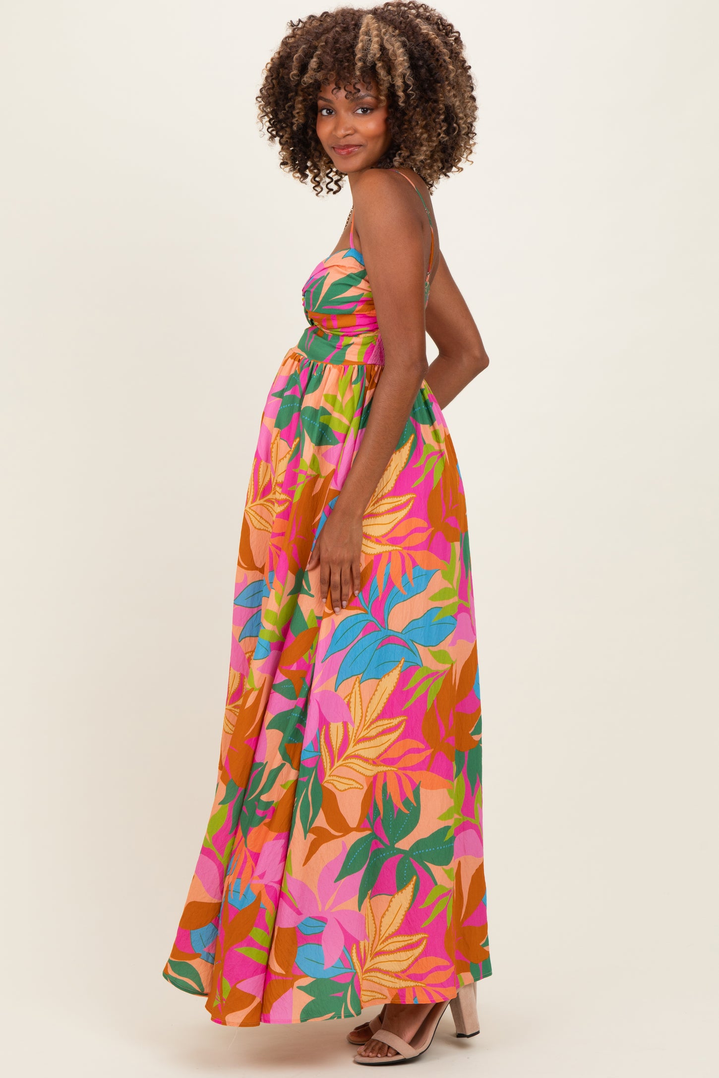 woman wearing a colorful floral maternity maxi dress with a fitted bodice and flowing skirt, showing baby bump