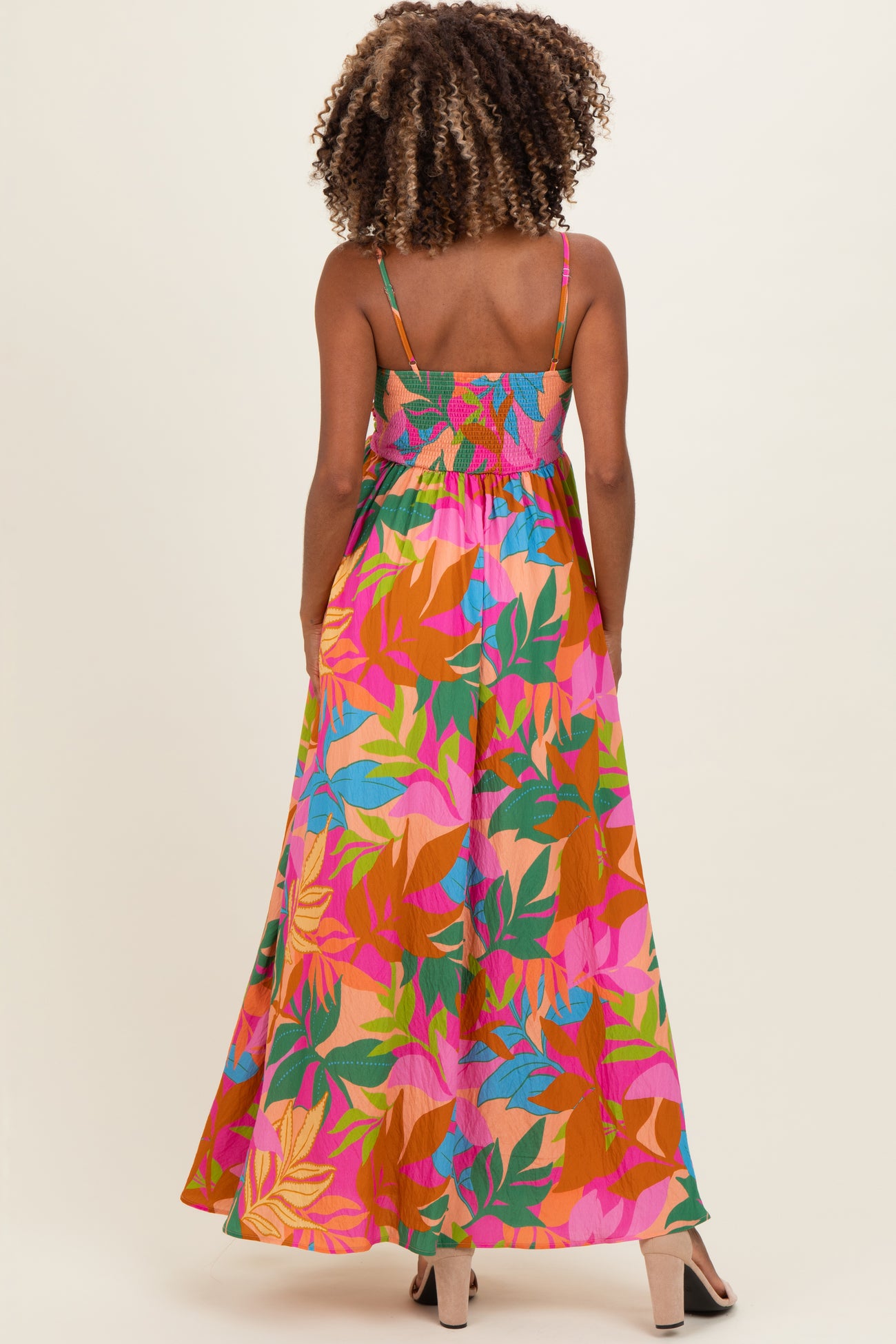woman wearing a colorful floral print maxi maternity dress with spaghetti straps and smocked bodice, showing a baby bump