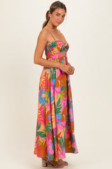 woman wearing a colorful floral print maxi dress with a fitted bodice and spaghetti straps