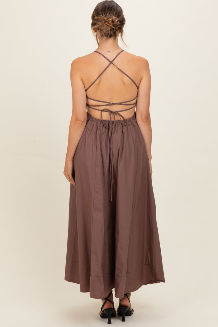 woman wearing a brown backless maternity dress with crisscross straps and a flowy skirt