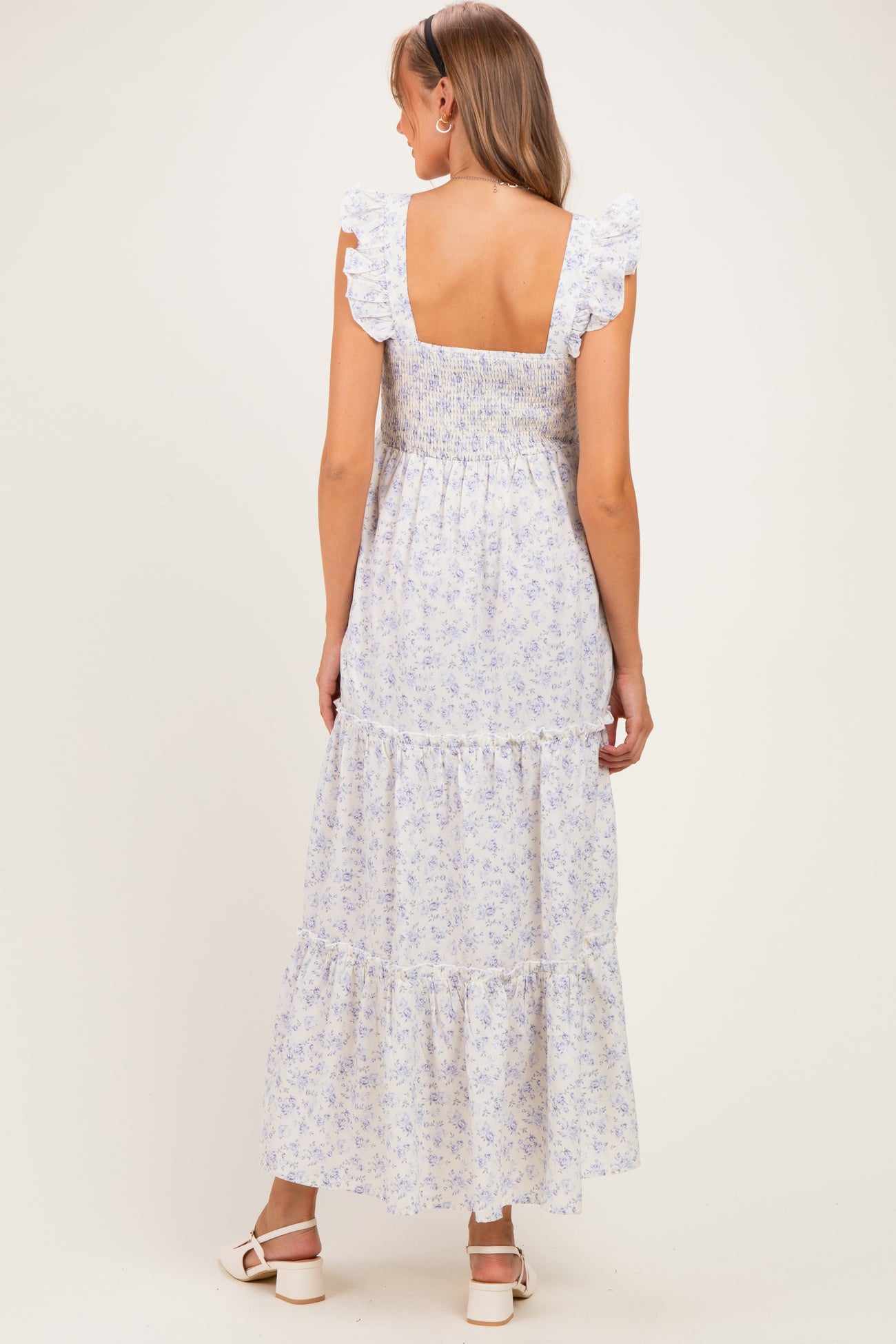 woman wearing a light blue floral maternity maxi dress with ruffles and a shirred back