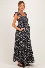 woman wearing a black floral maternity maxi dress with ruffle straps and pockets, showing her baby bump