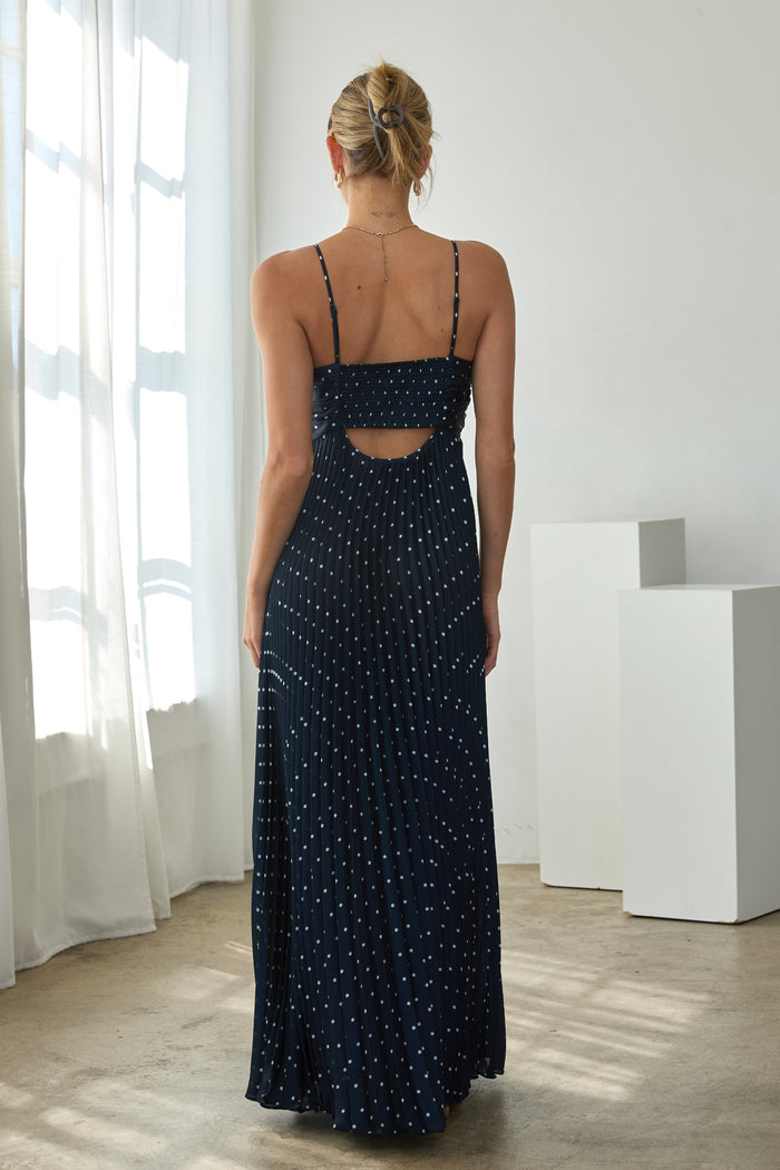 woman wearing a navy blue maxi dress with thin straps and a cutout back detail