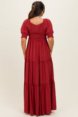 woman wearing a red maternity maxi dress with short puff sleeves and tiered skirt, showing back view