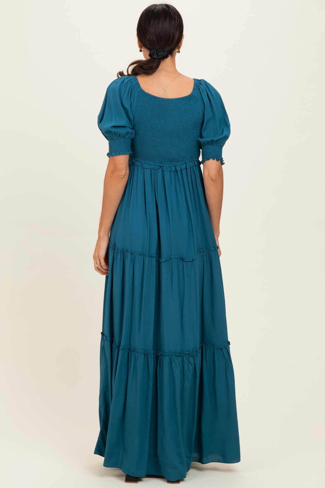 woman wearing a teal puff sleeve maxi dress with a smocked bodice and tiered skirt, shown from the back