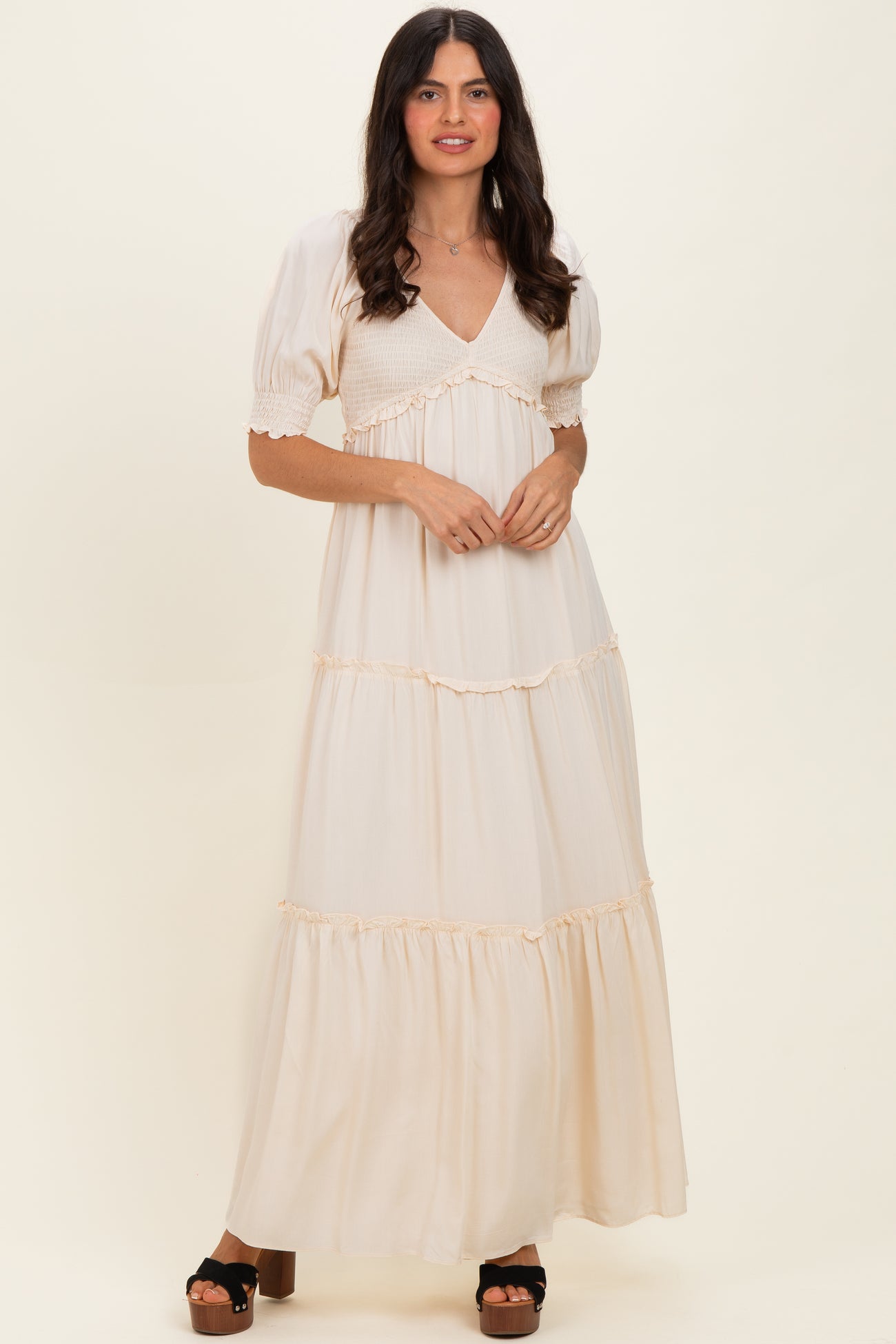 woman wearing a cream-colored maxi dress with puff sleeves and tiered ruffle detailing