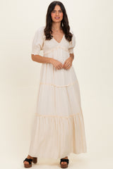 woman wearing a cream-colored maxi dress with puff sleeves and tiered ruffle detailing