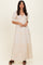 woman wearing a cream-colored maxi dress with puff sleeves and tiered ruffle detailing