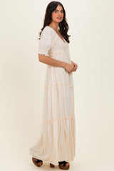 woman wearing a cream maxi dress with puffed sleeves and smocked bodice, standing sideways against a light backdrop