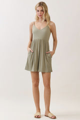 woman wearing a khaki green sleeveless dress with a fitted bodice and flared skirt, featuring pockets