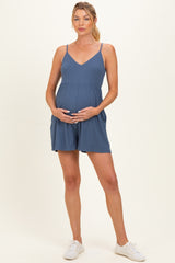 woman wearing a blue sleeveless maternity romper and holding her baby bump