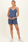 woman wearing a blue sleeveless maternity romper and holding her baby bump