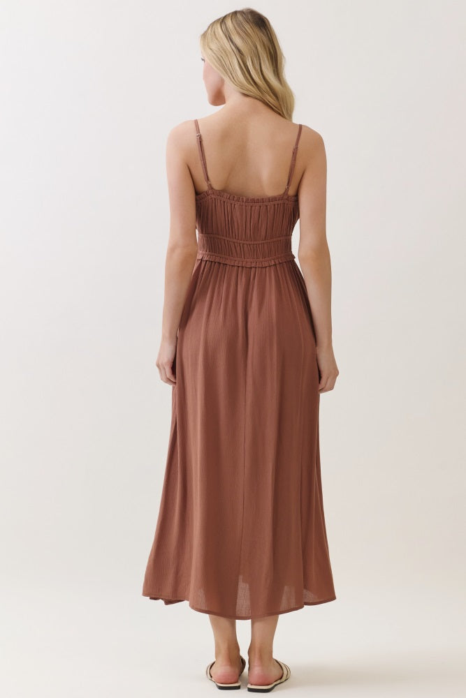 woman wearing a brown sleeveless maxi dress with a smocked bodice and a flowy skirt, viewed from the back