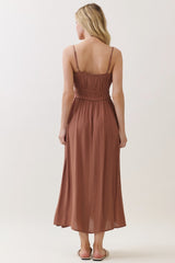woman wearing a brown sleeveless maxi dress with a smocked bodice and a flowy skirt, viewed from the back