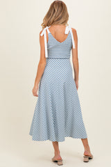 woman wearing a blue and white striped maternity dress with tie straps and a flared skirt, showing her back