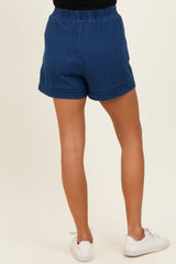 woman wearing dark blue denim shorts with embroidered hem and an elastic waistband, viewed from the back