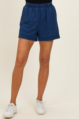 woman wearing dark blue elastic waistband shorts with decorative stitching and white sneakers