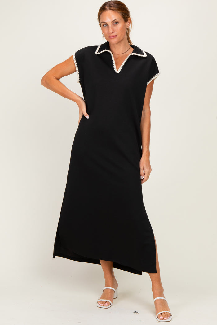 woman wearing a black maxi dress with a white collar and side slit, standing with one hand on her hip