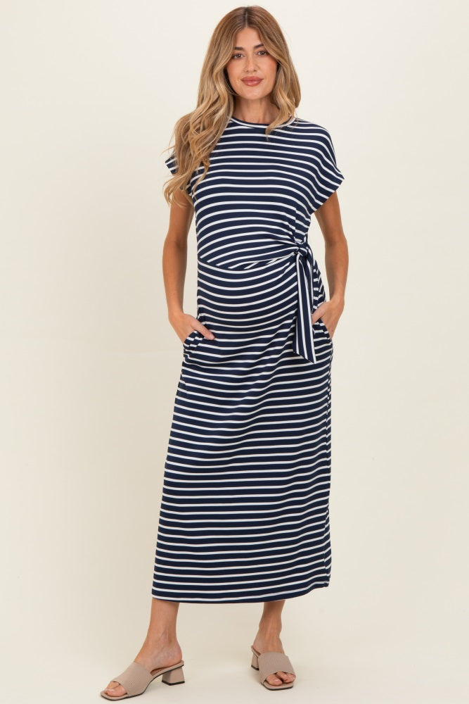 woman wearing a navy and white striped maternity maxi dress with pockets and a tie detail, showcasing her baby bump