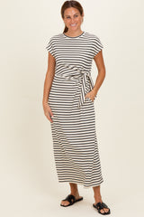 woman wearing a striped maxi dress with short sleeves and a side tie, posed with hands in pockets