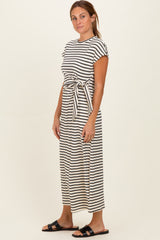 woman wearing a striped maxi dress with short sleeves and a tie waist detail, standing on a neutral background