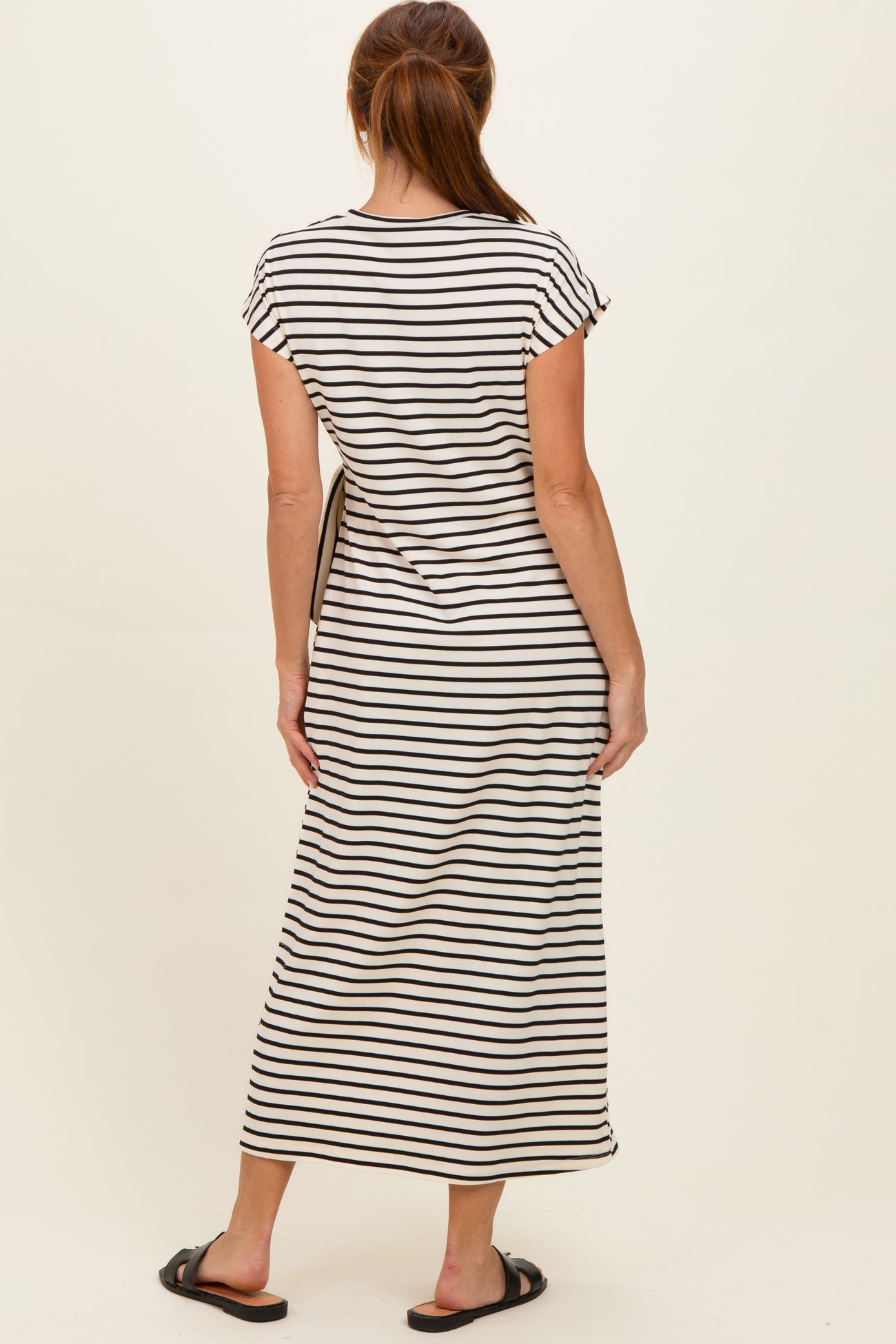 woman wearing a black and white striped short sleeve maxi dress, seen from the back