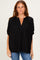 woman wearing a black loose-fit striped blouse with a v-neck and short sleeves, paired with blue jeans