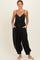 woman wearing a black spaghetti strap jumpsuit with button details and pockets, styled with flat sandals