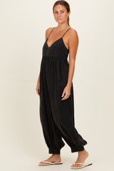 woman wearing a black sleeveless jumpsuit with a v-neckline and button details, styled with relaxed tapered legs