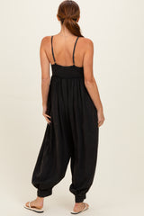 woman wearing a black smocked back jumpsuit with wide leg and spaghetti straps