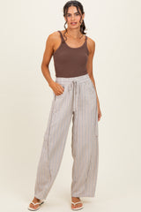 woman wearing a brown tank top and light striped wide-leg pants with side pockets