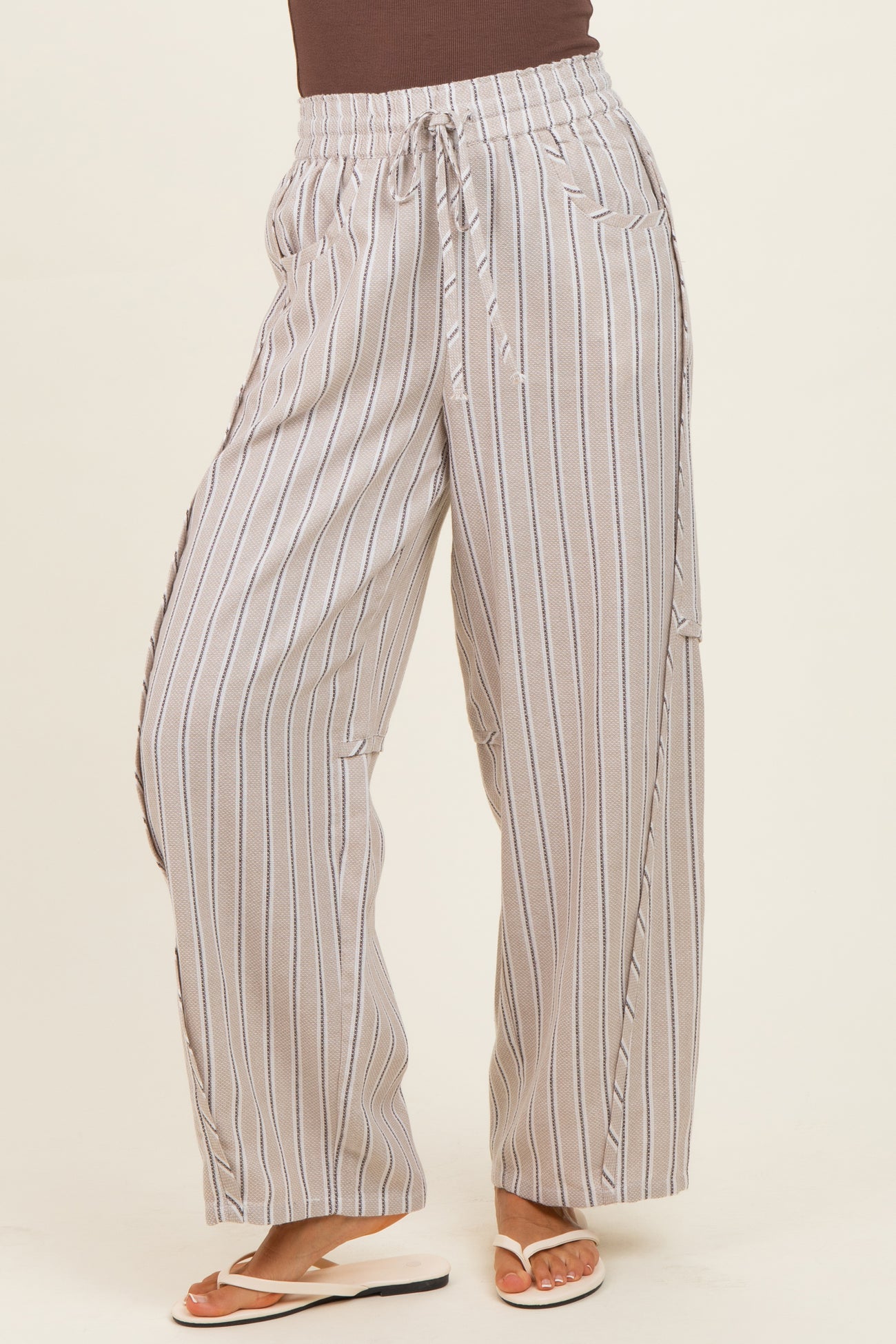 woman wearing beige and white striped wide-leg pants with a drawstring waist and side slits