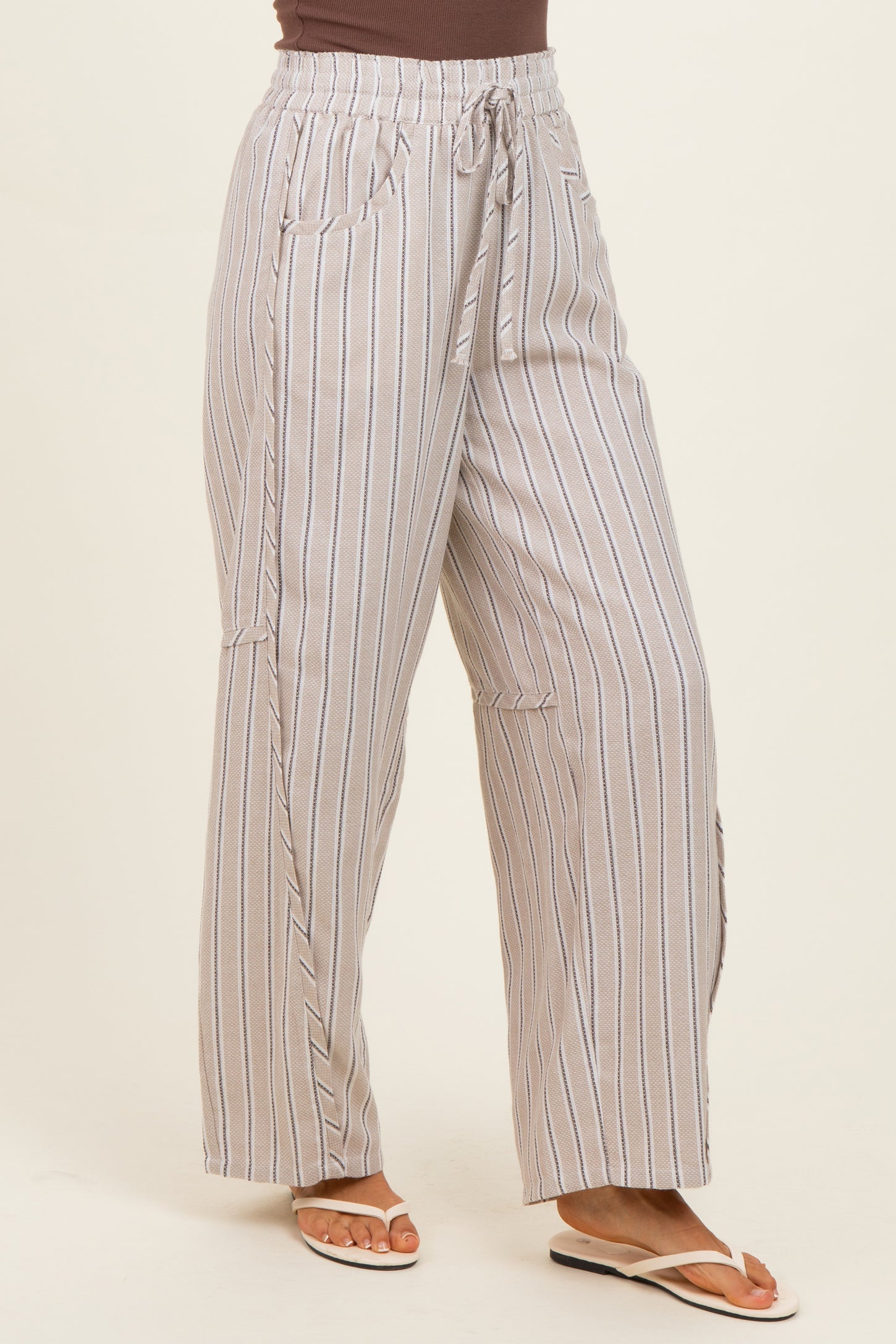 woman wearing light brown and cream striped wide-leg pants with a drawstring waist and side pockets