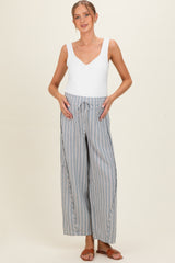 woman wearing a white sleeveless maternity top and striped wide-leg maternity pants with side pockets