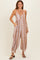 woman wearing a floral print sleeveless jumpsuit with pockets and comfortable fit, styled with brown sandals