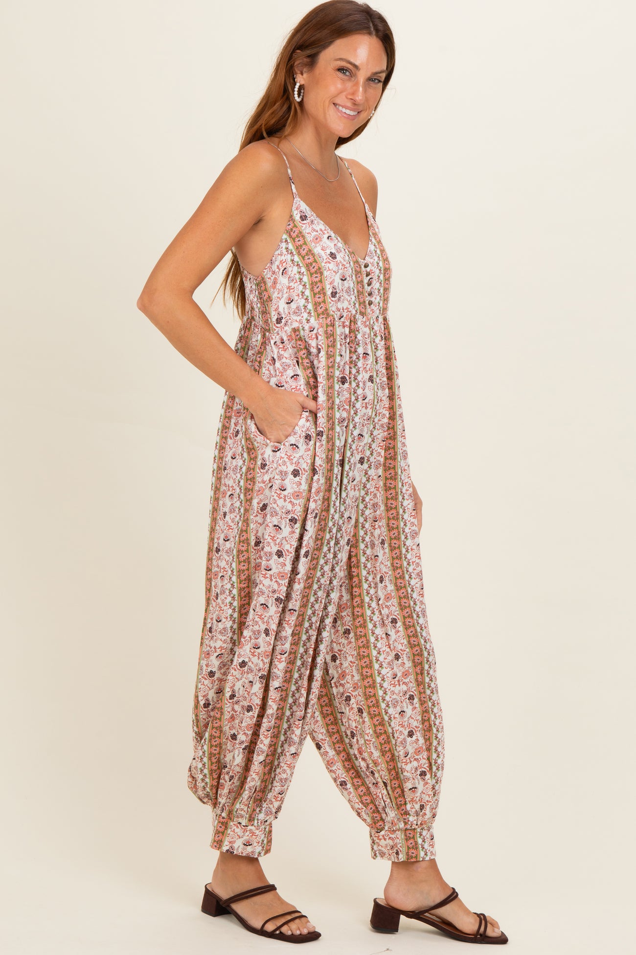 woman wearing a floral patterned jumpsuit with a v-neckline and pockets, styled with flat sandals