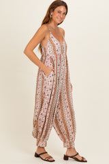 woman wearing a floral patterned jumpsuit with a v-neckline and pockets, styled with flat sandals