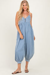 woman wearing a light blue denim jumpsuit with a button detail and balloon-style legs, styled with flip-flops