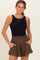 woman wearing a black sleeveless maternity bodysuit and brown high-waisted shorts with pockets