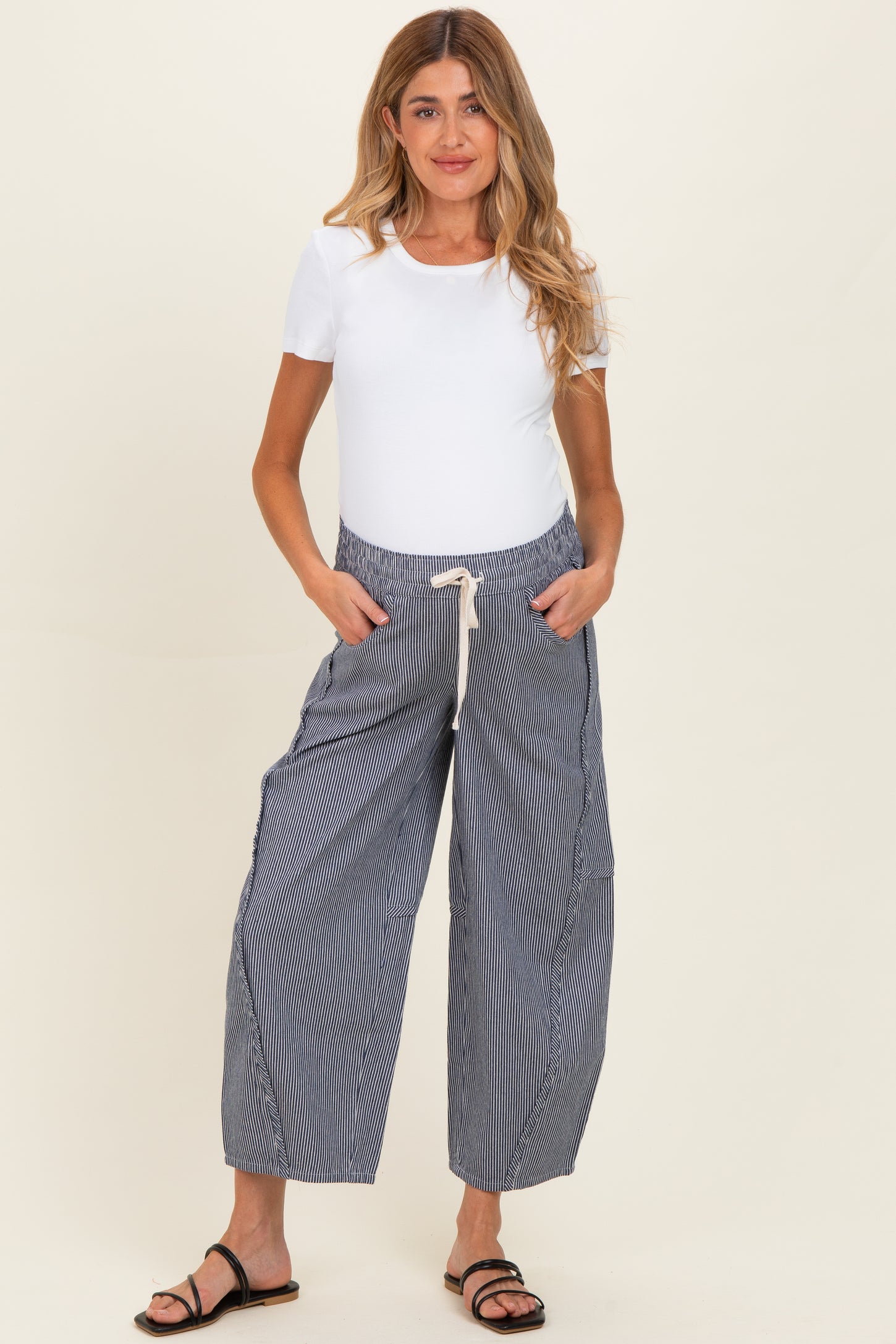 woman wearing a white short sleeve top and blue striped maternity pants with an elastic waistband and pockets