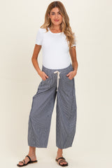 woman wearing a white short sleeve top and blue striped maternity pants with an elastic waistband and pockets