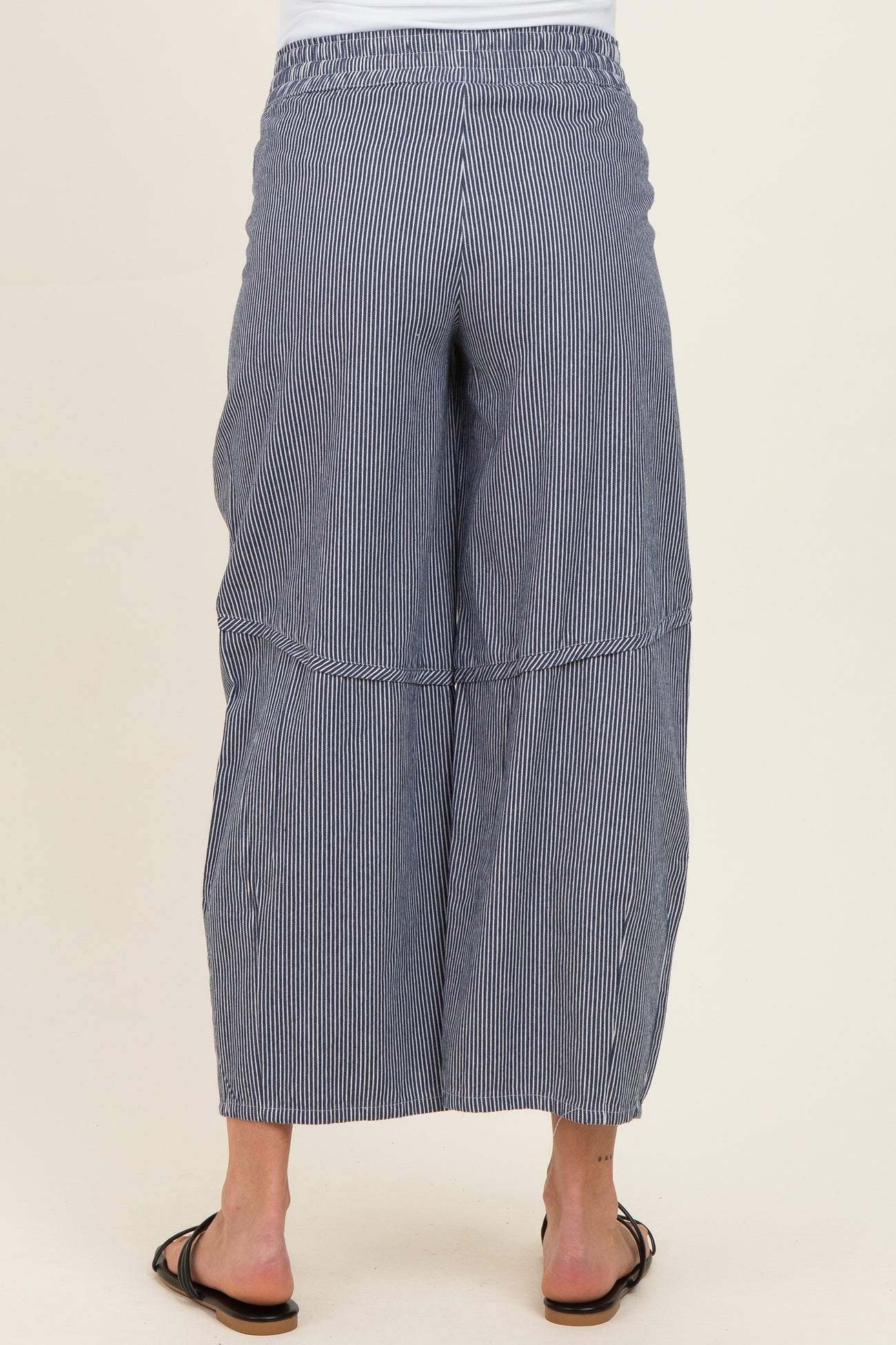 woman wearing black and white striped wide leg maternity pants, showing the back view with an elastic waistband