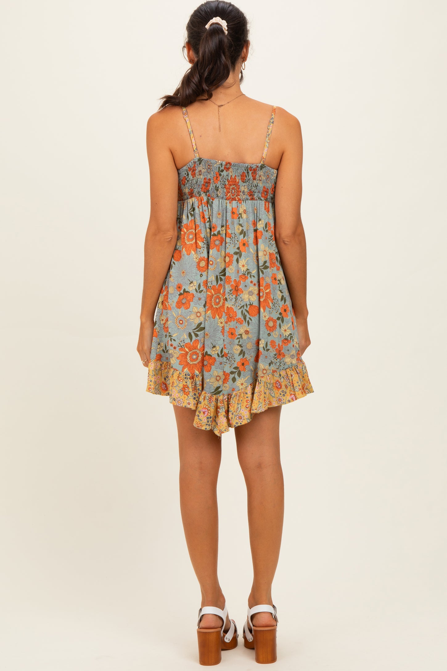 woman wearing a blue floral sundress with a smocked bodice and ruffled hem, seen from the back