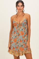 woman wearing a floral print sundress with spaghetti straps and a ruffled hem in shades of orange and blue