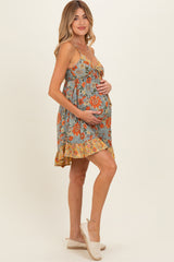 woman wearing a floral print maternity dress in blue and orange, holding her baby bump