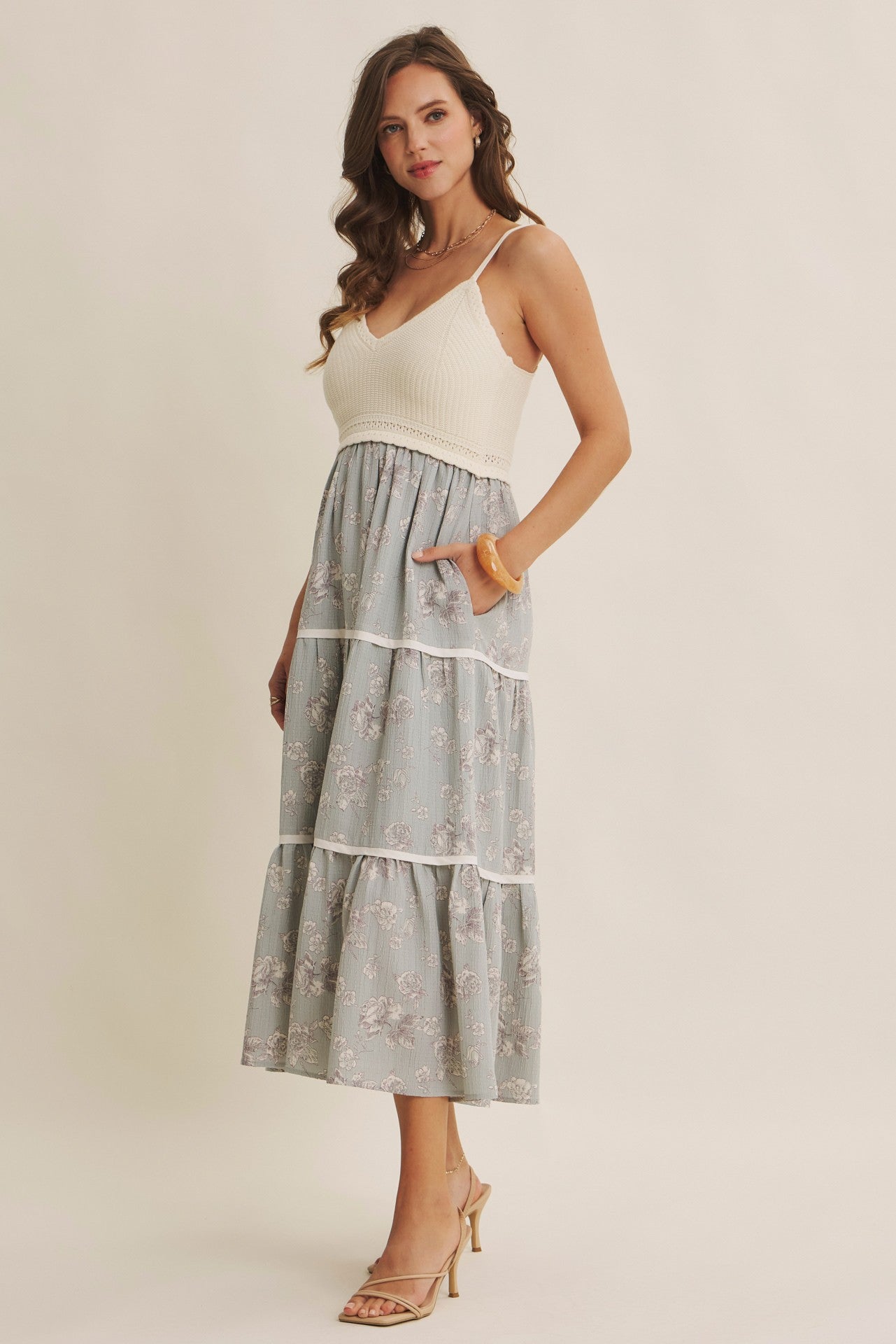 woman wearing a cream knit bodice and a blue floral tiered maxi dress with pockets and heels