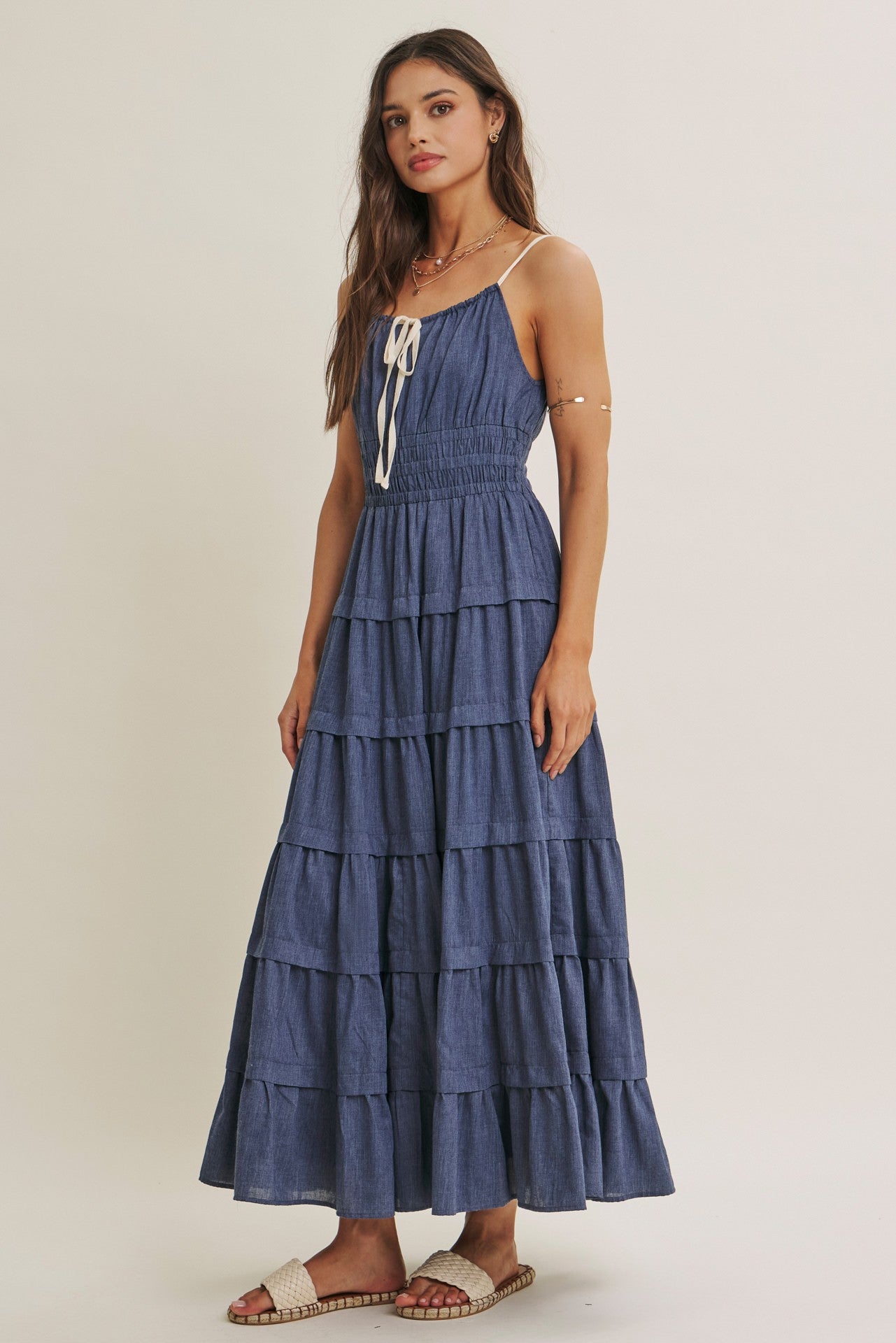woman wearing a navy blue tiered maxi dress with spaghetti straps and a tied front detail