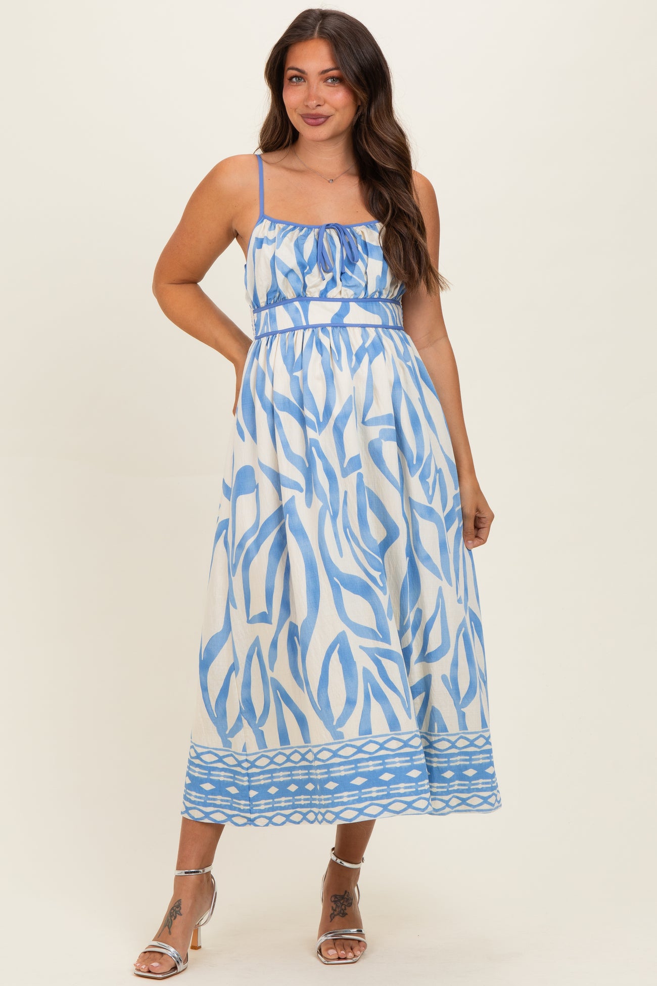 woman wearing a white maternity dress with blue abstract patterns and adjustable spaghetti straps