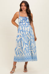 woman wearing a white maternity dress with blue abstract patterns and adjustable spaghetti straps